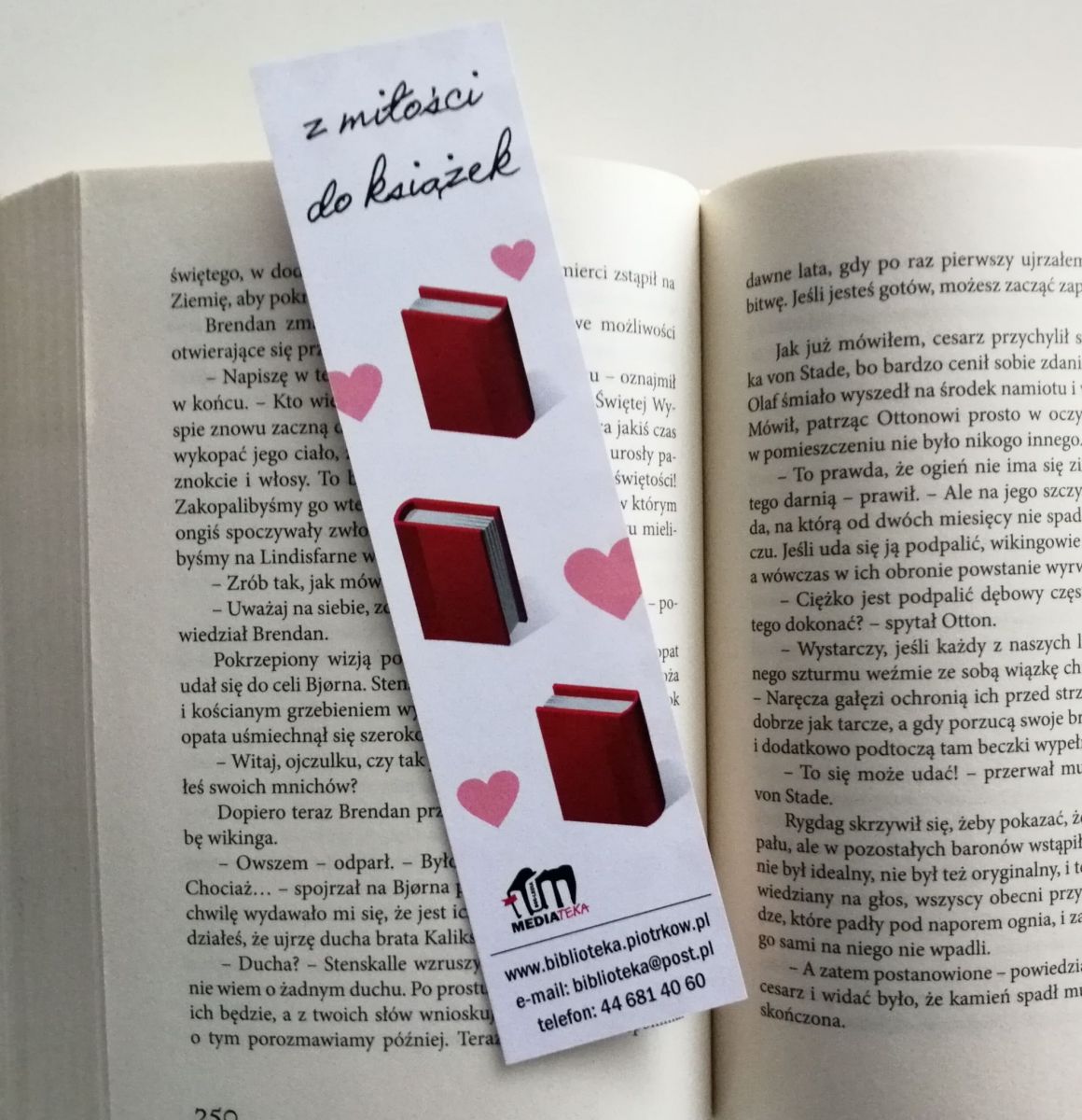 Zdjęcie przedstawia otwartą książkę fabularną, a na niej zakładka z napisem "Z miłości do książek", serduszkami i książkami.