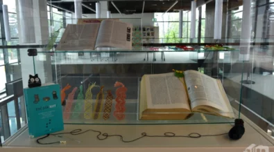 Na zdjęciu widoczna jest szklana gablota, w której zaprezentowano otwartą książkę oraz kolorowe zakładki ułożone obok, na jasnym tle. Ekspozycja nawiązuje do czytelnictwa i estetyki książki, a w tle widoczne są kolejne gabloty wystawowe Mediateki 800-lecia.