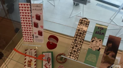 W szklanej gablocie wyeksponowane są kolorowe zakładki do książek, drobne grafiki oraz niewielkie przedmioty użytkowe o dekoracyjnym charakterze. Zdjęcie przedstawia fragment wystawy „Pomiędzy stronami” prezentowanej w Mediatece 800-lecia.