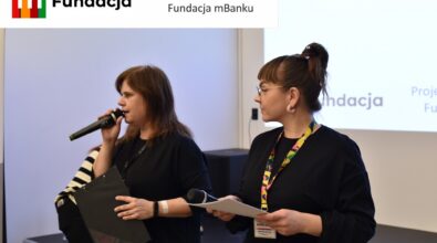 Dwie kobiety wygłaszają przemówienie przed publicznością. Na górze logotyp Fundacji mBanku.