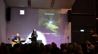 Kobieta śpiewa na scenie, mężczyzna obok gra na gitarze.