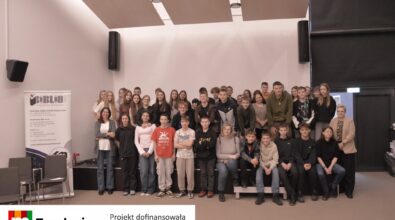 Grupa młodych uczestników pozuje wspólnie w przestrzeni bibliotecznej. Na dole logotyp Fundacji mBanku.