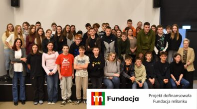 Grupa około pięćdziesięciu młodych uczestników wraz z opiekunami pozuje wspólnie do fotografii. Na dole logotyp Fundacji mBanku.