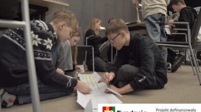 Uczniowie pracują wspólnie nad dużą papierową konstrukcją. Na dole logotyp Fundacji mBanku.