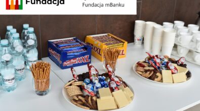 Stół z przekąskami i wodą mineralną. Na górze logotyp Fundacji mBanku.