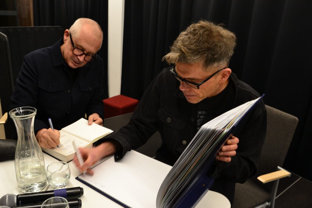 Goście spotkania podpisują książki i kronikę MBP.