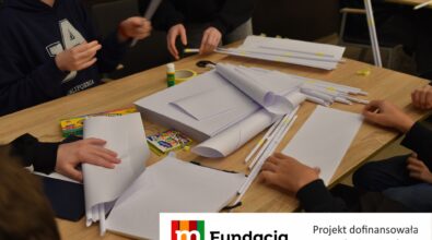 Uczestnicy konkursu tworzą konstrukcje z papierowych rurek, taśmy i kredek. Na dole logotyp Fundacji mBanku.