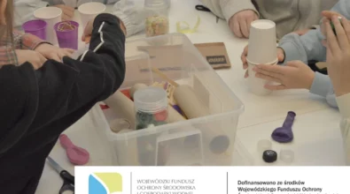 Dzieci siedzą przy stole i wspólnie pracują nad konstrukcjami z materiałów z recyklingu, wykorzystując papierowe kubki, rolki tekturowe, pojemniki plastikowe oraz drobne elementy plastyczne. Na dole zdjęcia widoczne są logotypy oraz informacja o dofinansowaniu zadania ze środków Wojewódzkiego Funduszu Ochrony Środowiska i Gospodarki Wodnej w Łodzi.