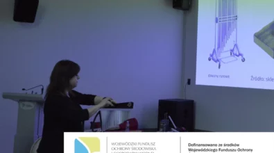 Na zdjęciu widoczna jest prowadząca warsztaty, która prezentuje dzwony rurowe podczas zajęć edukacyjnych „Muzyka z odpadów” w Mediatece. W tle wyświetlana jest prezentacja multimedialna, a wydarzenie realizowane jest w ramach zadania EkoTEKA, dofinansowanego ze środków Wojewódzkiego Funduszu Ochrony Środowiska i Gospodarki Wodnej w Łodzi.