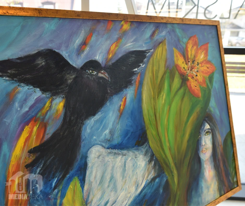 Fragment obrazu malarskiego przedstawiający czarnego ptaka z rozpostartymi skrzydłami na tle intensywnie kolorowanej, symbolicznej kompozycji z motywami roślinnymi i kobiecą twarzą. Zdjęcie ukazuje detal jednego z obrazów prezentowanych na wystawie malarstwa Joanny Prus w Mediatece 800-lecia.