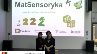 Dwie prowadzące stoją na scenie przed dużym ekranem z prezentacją zatytułowaną „MatSensoryka 4”. Na slajdzie widoczne są grafiki liczb oraz informacje o autorach materiału edukacyjnego. Na dole prezentacji znajdują się logotypy partnerów i instytucji wspierających projekt, w tym Fundacji mBanku, Miasta Piotrków Trybunalski oraz Miejskiej Biblioteki Publicznej. Wydarzenie odbywa się w przestrzeni Mediateki 800-lecia.