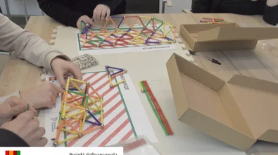 Dzieci wspólnie budują przestrzenne konstrukcje z kolorowych patyczków i metalowych kulek, łącząc elementy w stabilne trójkątne układy przypominające most lub kratownicę. Na stole znajdują się zestawy konstrukcyjne, instrukcje oraz przygotowane elementy, z których uczestnicy tworzą własne modele. Zajęcia rozwijają wyobraźnię przestrzenną, logiczne myślenie oraz umiejętność współpracy podczas warsztatów realizowanych w Mediatece 800-lecia w ramach projektu „MatSensoryka 4”, dofinansowanego przez Fundację mBanku.