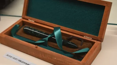 W gablocie ekspozycyjnej zaprezentowane jest pióro wieczne umieszczone w drewnianym etui wyściełanym zielonym materiałem, opatrzone opisem informacyjnym. Zdjęcie przedstawia fragment wystawy „Historia i teraźniejszość Polski – piórem wiecznym pokazana” prezentowanej w Miejskiej Bibliotece Publicznej im. Adama Próchnika.