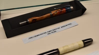 W gablocie wystawowej zaprezentowane są pióra wieczne o zróżnicowanym wyglądzie i kolorystyce, ułożone na jasnym tle wraz z opisami. Zdjęcie przedstawia fragment wystawy dr. n. med. Andrzeja Papiewskiego pt. „Historia i teraźniejszość Polski – piórem wiecznym pokazana”, prezentowanej w Miejskiej Bibliotece Publicznej im. Adama Próchnika.