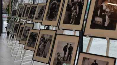 Na sztalugach ustawionych w długim rzędzie zaprezentowane są oprawione czarno-białe fotografie przedstawiające sceny z życia codziennego i portrety ludzi. Zdjęcie ukazuje fragment wystawy fotograficznej prezentowanej w przestrzeni Miejskiej Biblioteki Publicznej.