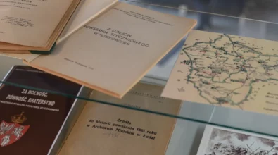 W szklanej gablocie wystawowej ułożone są archiwalne książki, broszury i materiały kartograficzne związane z historią XIX wieku. Zdjęcie przedstawia fragment wystawy historycznej prezentowanej w Miejskiej Bibliotece Publicznej im. Adama Próchnika.