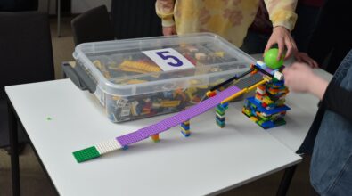 Na zdjęciu widać tor dla kuli zbudowany z klocków LEGO. Przypomina on zjeżdżalnię. W tle widać pudełko z klockami, na którego przykrywce znajduje się cyfra 5. Zdjęcie: MBP.