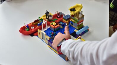 Na zdjęciu widać wykonaną z klocków LEGO budowlę. Na jednej z wież znajduje się plastikowy żółty ponton. Większe, czerwone pontony można zauważyć za budowlą. Na pierwszym planie widać dłoń dziecka, które pokazuje kciuka w górę. Zdjęcie: MBP.