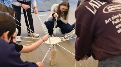 Zdjęcie przedstawia grupę nastolatków układających wieżę. Każde z nich trzyma sznurek, za pomocą którego utrzymując równowagę na ustawioną wieżę kładą kolejny stopień. Wydają się być zadowoleni. Jedna dziewczyna znajdująca się w centrum zdjęcia kuca. Zdjęcie: MBP.