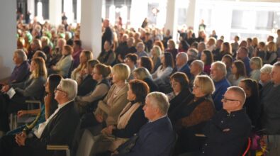Na zdjęciu widoczna jest licznie zgromadzona publiczność siedząca na krzesłach w przestronnej, nowoczesnej sali Mediateki. Uczestnicy wydarzenia, w różnym wieku, siedzą obok siebie w rzędach i z uwagą patrzą w jednym kierunku, skupieni na trwającym wystąpieniu poza kadrem. Wnętrze jest jasne, z białymi filarami i sufitowym oświetleniem, a atmosfera spotkania ma charakter oficjalny i spokojny, podkreślający duże zainteresowanie wydarzeniem kulturalnym.
