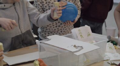 Zdjęcie przedstawia dzieci podczas zajęć. Na stoliku, przy którym się znajdują leży pudełko wypełnione materiałami wykorzystywanymi do pracy. Jedna z dziewczynek trzyma w dłoni napompowanego balona. Zdjęcie: MBP.