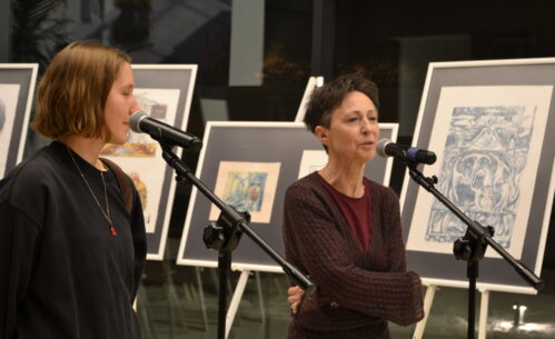 Dyrektor MBP i autorka wystawy przy mikrofonach. W tle sztalugi z grafikami.