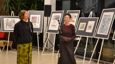 Dyrektor MBP i autorka wystawy przy mikrofonach. W tle sztalugi z grafikami.