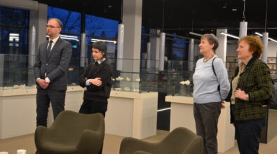 Zdjęcie uczestników wystawy, w tle gabloty z rzeźbami.