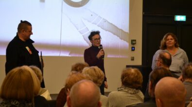 Na zdjęciu widoczna jest pani dyrektor Mediateki 800-lecia przemawiająca do zgromadzonej publiczności. Stoi przed ekranem projekcyjnym, trzyma mikrofon i zwraca się do uczestników wydarzenia siedzących na sali.