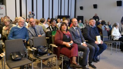 Na zdjęciu widać licznie zgromadzonych uczestników siedzących na krzesłach w sali spotkań, wśród nich kobiety i mężczyzn w różnym wieku, oczekujących na rozpoczęcie wydarzenia. Uczestnicy ubrani są w stroje codzienne i półformalne, a przestrzeń ma charakter konferencyjny i wskazuje na spotkanie lub wykład organizowany w bibliotece.