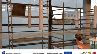 Widok rusztowania stojącego przy dużym oknie – prace techniczne realizowane w ramach projektu wspieranego przez fundusze europejskie. Na dole zdjęcia widoczne są logotypy instytucji wspierających projekt.