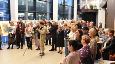 Na zdjęciu widoczna jest licznie zgromadzona publiczność stojąca w przestrzeni wystawowej podczas otwarcia wystawy, uważnie słuchająca wystąpienia artystki. Uczestnicy w różnym wieku wypełniają salę, a kadr oddaje uroczysty i integrujący charakter wydarzenia kulturalnego.