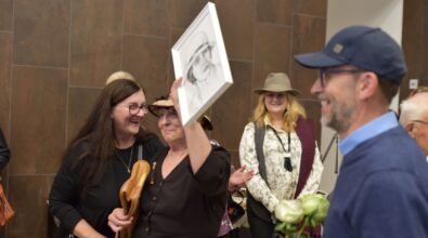 Artystka z uśmiechem pokazuje obraz - jeden z upominków od uczestnika wernisażu.