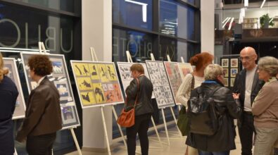 Na zdjęciu widoczni są uczestnicy oglądający plansze wystawy prezentowane na stojakach w przestrzeni galerii. Osoby zatrzymują się przy poszczególnych pracach, a kadr oddaje kameralny charakter spotkania oraz zaangażowanie odbiorców w odbiór prezentowanej ekspozycji.