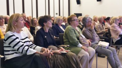 Na zdjęciu widoczna jest licznie zgromadzona publiczność siedząca na sali podczas otwarcia wystawy Agnieszki Illinicz-Kiełkiewicz „I tak to w życiu (u)bywa...”, w pierwszym rzędzie siedzi pani dyrektor Miejskiej Biblioteki Publicznej. Uczestnicy spotkania uważnie słuchają opowieści artystki o swojej twórczości.