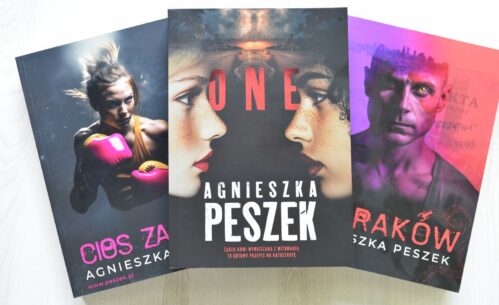 Trzy egzemplarze książki autorstwa Agnieszka Peszek ustawione obok siebie, lekko pod kątem. W centrum znajduje się książka z wyraźnym tytułem „ONE”. Okładka przedstawia zbliżenia twarzy młodych osób skierowanych w różnych kierunkach, utrzymane w chłodnej kolorystyce. Po lewej stronie widoczna jest książka w odcieniach różu i fioletu z fragmentem tytułu „…es za”, a po prawej egzemplarz w ciemniejszych, purpurowych barwach z widocznym fragmentem tytułu „Rak…”. Wszystkie okładki tworzą spójną serię graficzną z portretami bohaterów i intensywnymi kolorami tła.