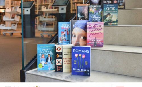 Na zdjęciu widzimy stos książek ułożonych na schodach w bibliotece. W tle znajduje się przestrzeń biblioteczna z regałami pełnymi książek oraz stanowiskami komputerowymi. Na pierwszym planie widoczne są okładki różnych powieści, m.in.: „Patrz ze mną w gwiazdy” Anny Szafrańskiej, „Romans” Sheryl Browne, „Pięcioro małych Indian” Michelle Good, „Spotkasz mnie nad jeziorem” Carley Fortune, „Oczy Mony” i inne. Na dole zdjęcia umieszczono logotypy: Narodowego Programu Rozwoju Czytelnictwa 2.0, Ministerstwa Kultury i Dziedzictwa Narodowego oraz Biblioteki Narodowej. Widnieje też informacja o dofinansowaniu ze środków Ministra Kultury w ramach realizacji NPRCz 2.0 na lata 2021–2025.