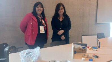 dwie osoby stojące przed stołem, na którym znajdują się różne przedmioty,takie jak drewniane klocki, lustra czy latarka służące do przeprowadzania eksperymentów.