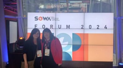 dwie osoby stojące przed dużym ekranem wyświetlającym informacje o 