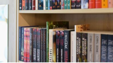 Na zdjęciu widać półki z książkami, które znajdują się w bibliotece. Na górnej półce można dostrzec różnorodne książki z literatury współczesnej, m.in. tytuły autorstwa Aliny Bożeny J., Joanny Jax, czy Krzysztofa Zajasa. Na dolnej półce widoczne są książki takich autorów jak Daniel Hurst, Marcin Walczak czy Paolo Cognetti. Półki są starannie zorganizowane, a książki ustawione pionowo, co ułatwia ich przeglądanie. Na dole zdjęcia znajdują się logotypy Narodowego Programu Rozwoju Czytelnictwa 2.0, Ministerstwa Kultury i Dziedzictwa Narodowego oraz Biblioteki Narodowej z informacją o dofinansowaniu w ramach NPRCz 2.0 na lata 2021–2025.