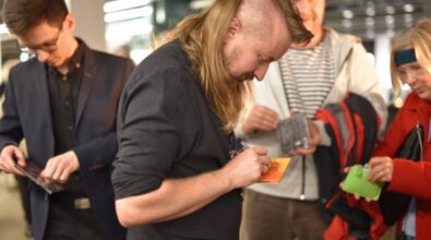 Gitarzyści podpisują płyty. W tle widać stojących w kolejce ludzi.