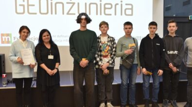 Grupa osób pozuje do zdjęcia na tle ekranu z napisem 