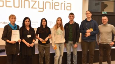 Grupa osób pozuje do zdjęcia na tle ekranu z napisem 