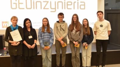 Grupa osób pozuje do zdjęcia na tle ekranu z napisem 