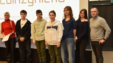 Grupa osób pozuje do zdjęcia na tle ekranu z napisem 