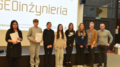 Grupa osób pozuje do zdjęcia na tle ekranu z napisem 