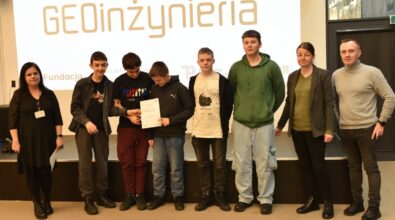 Grupa osób pozuje do zdjęcia na tle ekranu z napisem 