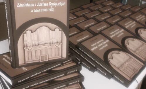 Na pierwszym planie wyeksponowany jest egzemplarz książki o tytule: „Działalność organmistrzowska Stanisława i Stefana Kukukowskich w latach (1879–1963)” autorstwa ks. Antoniego Pietrzyka M.S.F. Okładka jest w stonowanych odcieniach brązu, z grafiką przedstawiającą organy kościelne w centralnej części. W tle widoczne są kolejne egzemplarze książki starannie poukładane w rzędach.