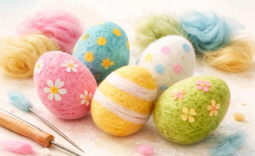 Na grafice widoczne są kolorowe, filcowane pisanki ozdobione wzorami kwiatów, kropek i pasków. Obok nich znajdują się kłębki wełny w pastelowych kolorach oraz narzędzia do filcowania.