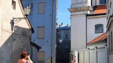 Kobieta w zwiewnej sukience robi zdjęcie kościoła w Rynku Trybunalskim.